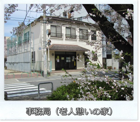 桜に囲まれた公園のそばに建つ2階建ての会館 事務局 正面.jpg